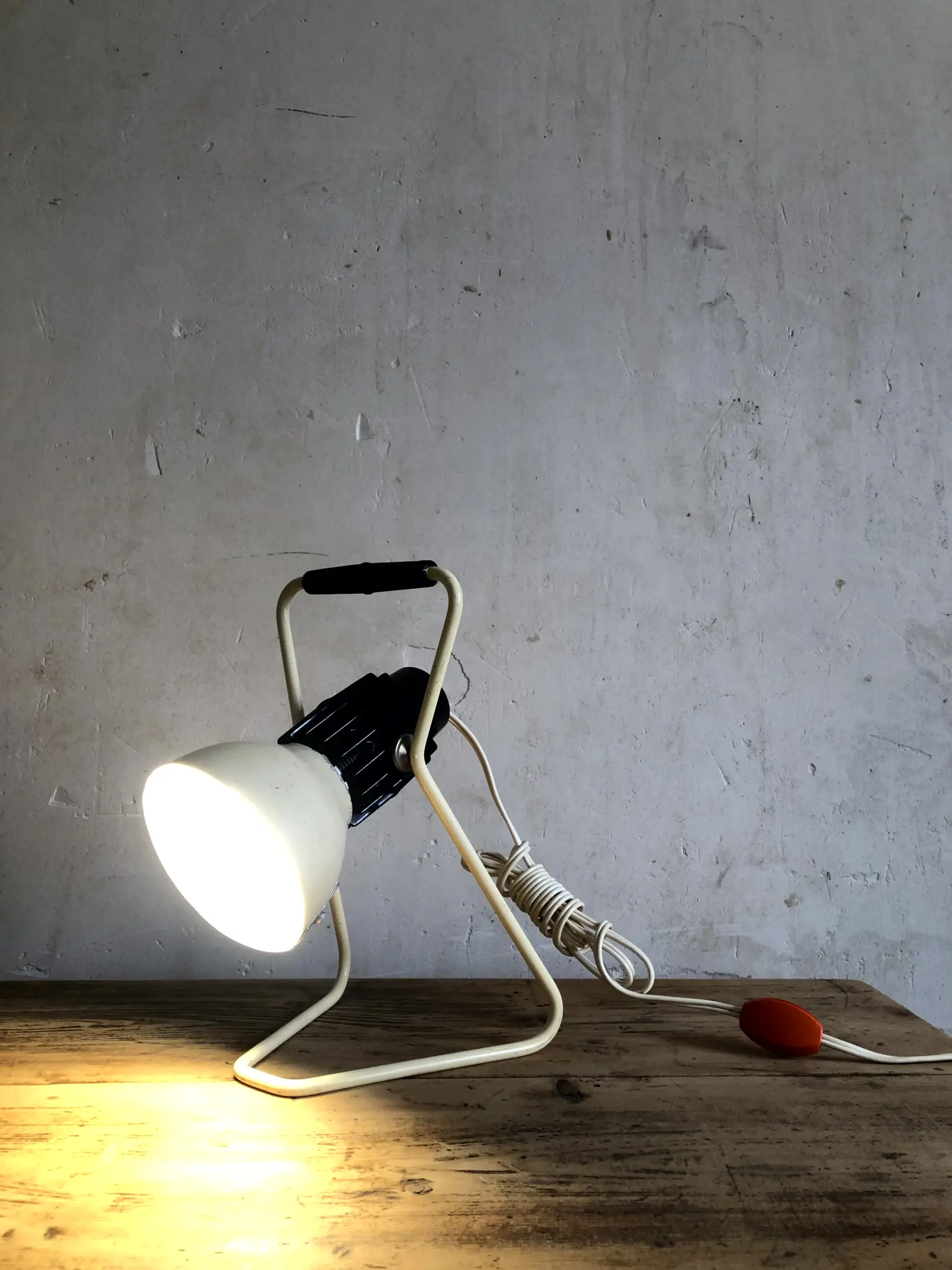 La lampe Omni allumée et posée sur un bureau, avec son câble d'alimentation