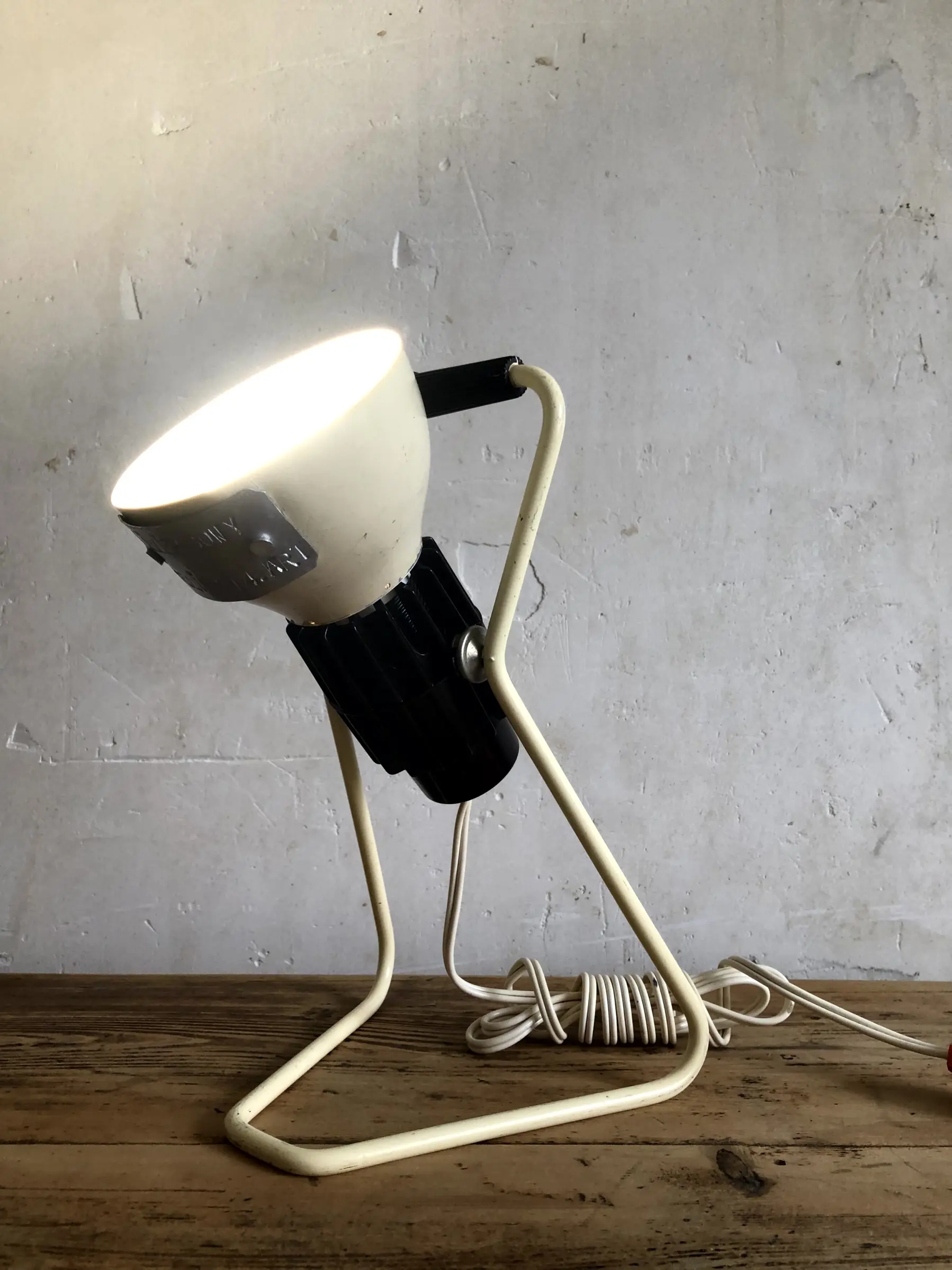 La lampe Omni allumée et posée sur un bureau, en position haute