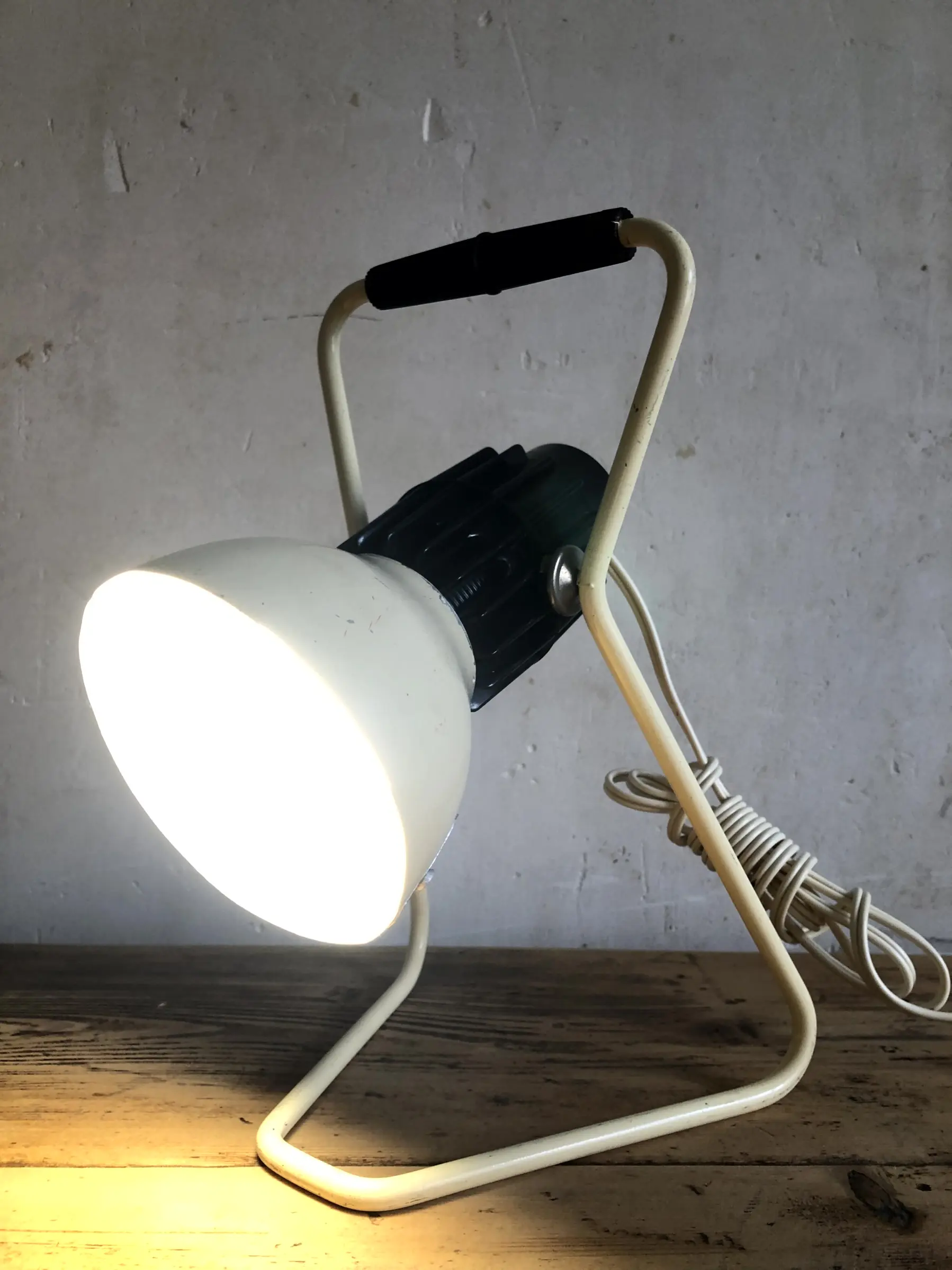 La lampe Omni allumée et posée sur un bureau, en position basse, vue rapproché