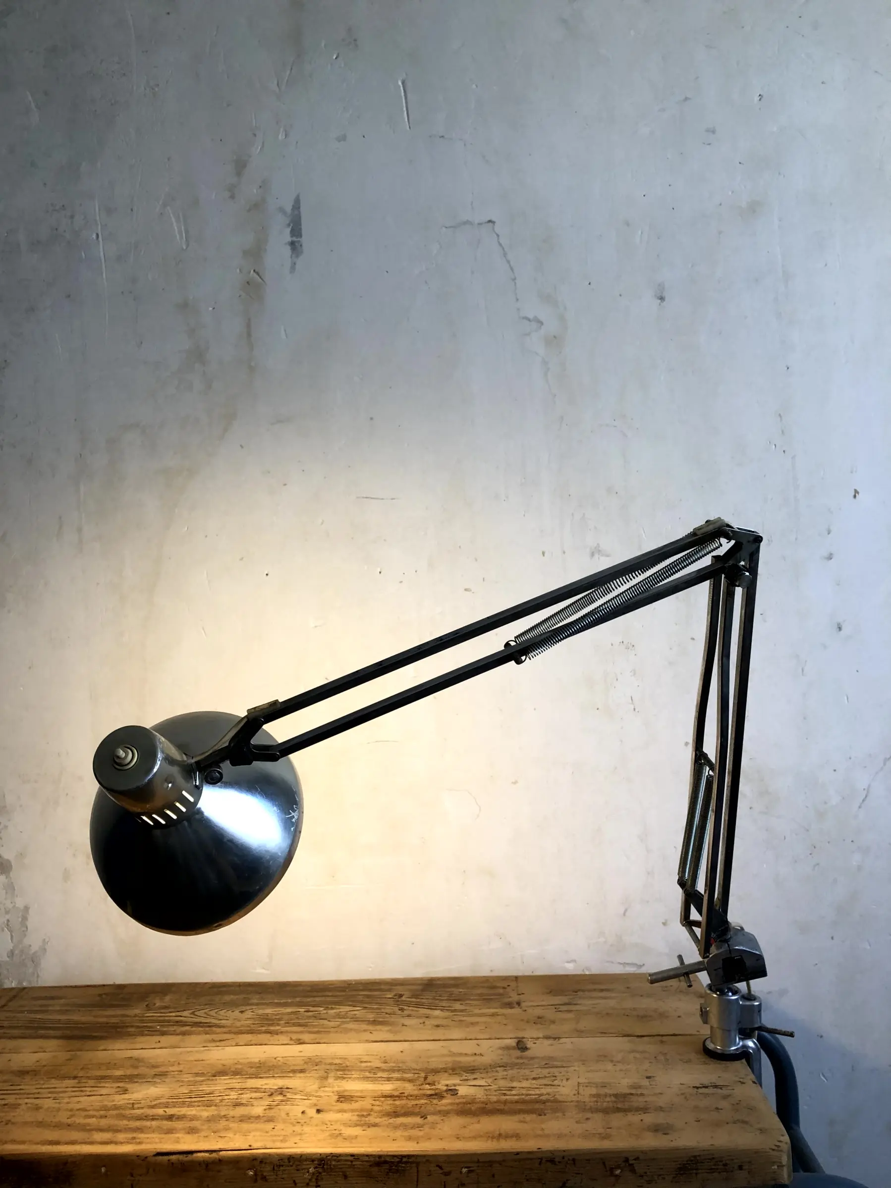 La lampe Stov allumée et fixée sur un bureau avec une rotation